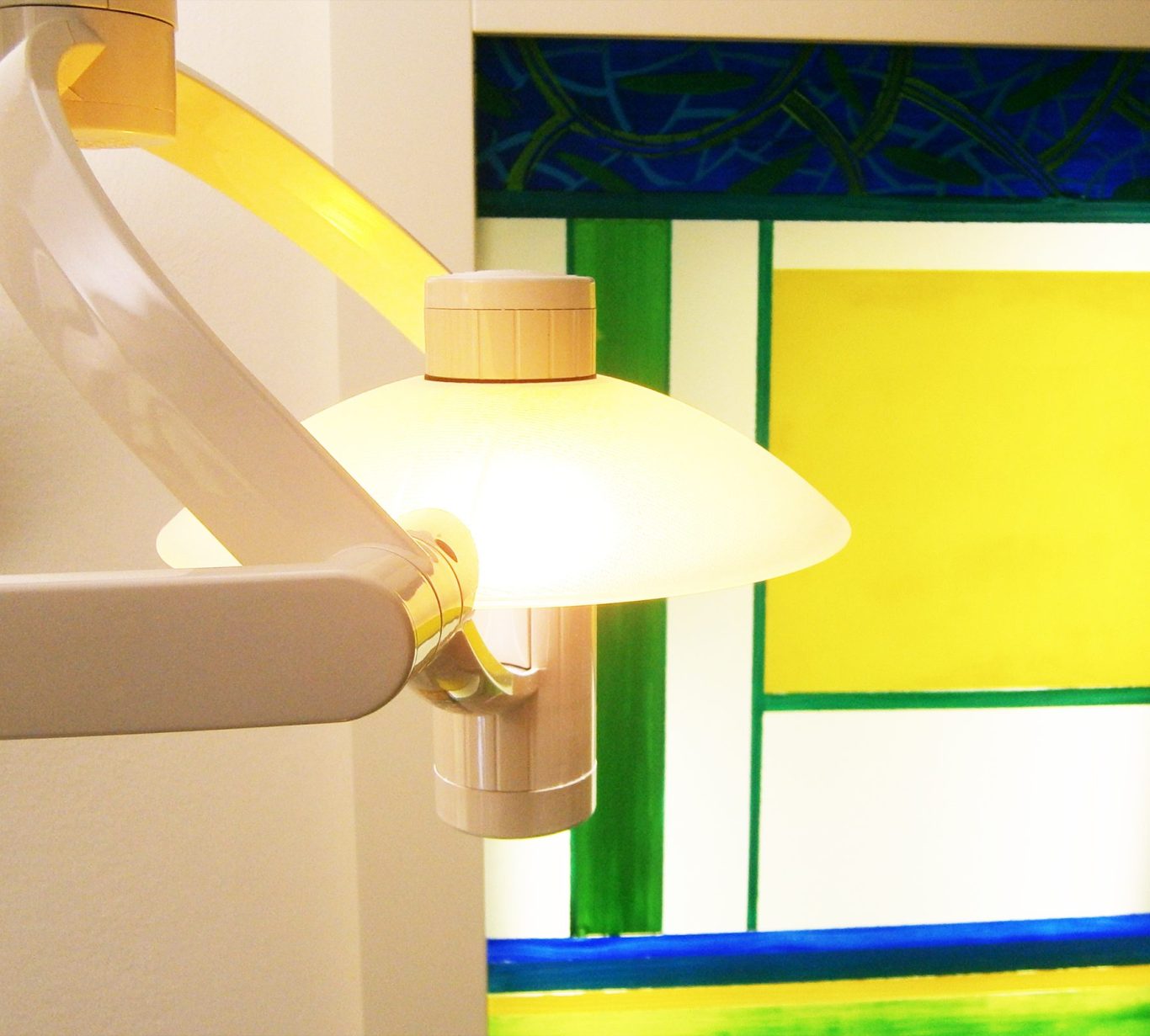 Lampe vor Hinterglasmalerei in Gelb, Blau, Grün: die Logofarben der Zahnarztpraxis Dr. Herbert Bruckbauer